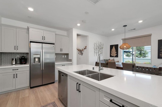 2051 Julie Dawn Pl, Escondido, CA 92026 - kitchen featuring stainless steel appliances, light countertops, light wood finished floors, decorative backsplash, and hanging light fixtures