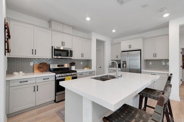 2051 Julie Dawn Pl, Escondido, CA 92026 - kitchen with stainless steel appliances, a kitchen island with sink, decorative backsplash, light wood-style flooring, and recessed lighting