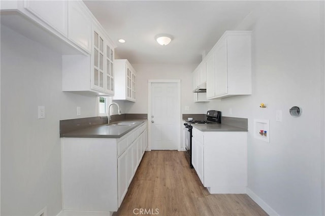 1435 E Colon St, Wilmington, CA 90744 - kitchen with black gas stove, under cabinet range hood, wood finished floors, glass insert cabinets, and white cabinets