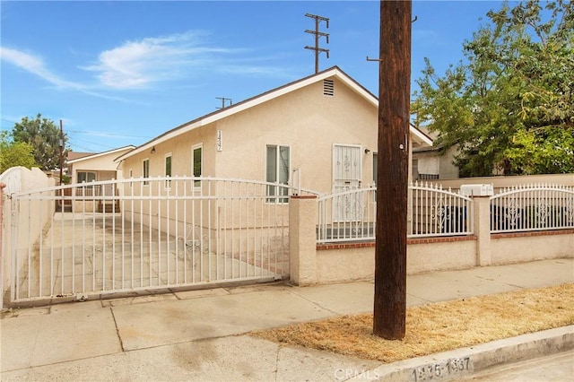 1435 E Colon St, Wilmington, CA 90744 - view of front of home with stucco siding, a fenced front yard, and a gate