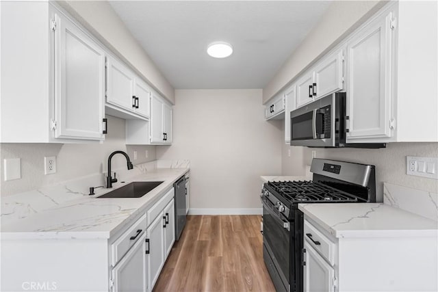 43441 30th St W Unit 3, Lancaster, CA 93536 - kitchen with stainless steel appliances, white cabinetry, light wood finished floors, and light stone countertops