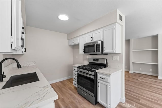 43441 30th St W Unit 3, Lancaster, CA 93536 - kitchen with appliances with stainless steel finishes, light stone counters, light wood finished floors, and white cabinets