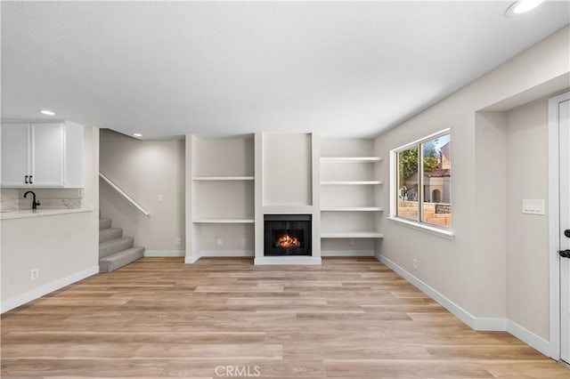 43441 30th St W Unit 3, Lancaster, CA 93536 - unfurnished living room featuring light wood-style flooring, recessed lighting, a warm lit fireplace, and stairway
