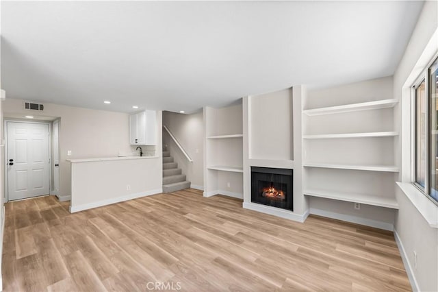 43441 30th St W Unit 3, Lancaster, CA 93536 - unfurnished living room featuring light wood finished floors, a lit fireplace, recessed lighting, and stairs
