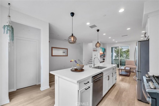791 S Mosaic St, Anaheim, CA 92805 - kitchen with stainless steel appliances, light wood-style flooring, white cabinets, a center island with sink, and light countertops