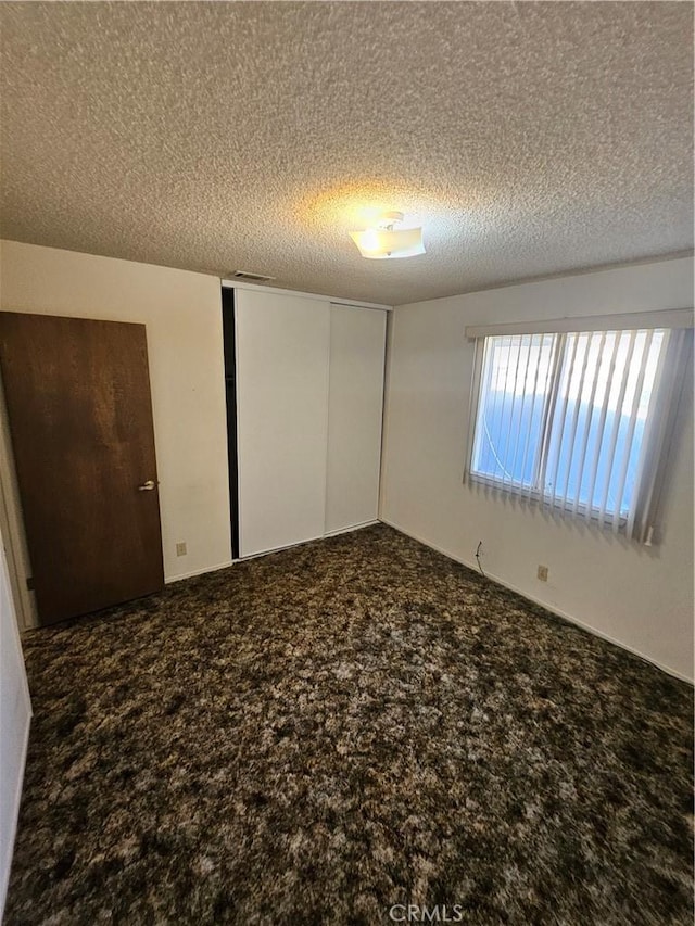 12546 Rain Shadow Rd, Victorville, CA 92395 - unfurnished bedroom with carpet, a textured ceiling, and a closet