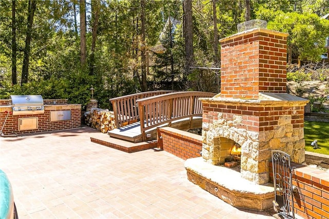 514 Riviera Dr, Lake Arrowhead, CA 92352 - view of patio featuring an outdoor brick fireplace, an outdoor kitchen, and view of wooded area