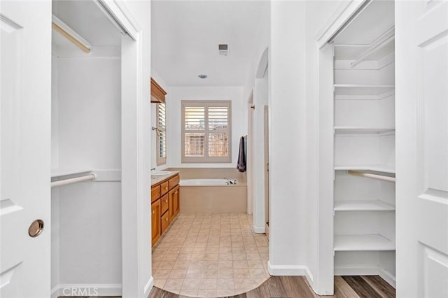 658 Tusky Ave, Los Banos, CA 93635 - full bathroom featuring a garden tub, vanity, a walk in closet, and wood finished floors