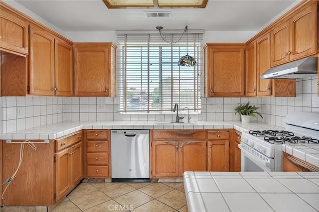 658 Tusky Ave, Los Banos, CA 93635 - kitchen featuring stainless steel dishwasher, under cabinet range hood, gas range gas stove, light tile patterned flooring, and decorative backsplash