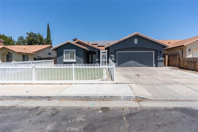 658 Tusky Ave, Los Banos, CA 93635 - view of front of house with a fenced front yard, an attached garage, concrete driveway, a tile roof, and solar panels