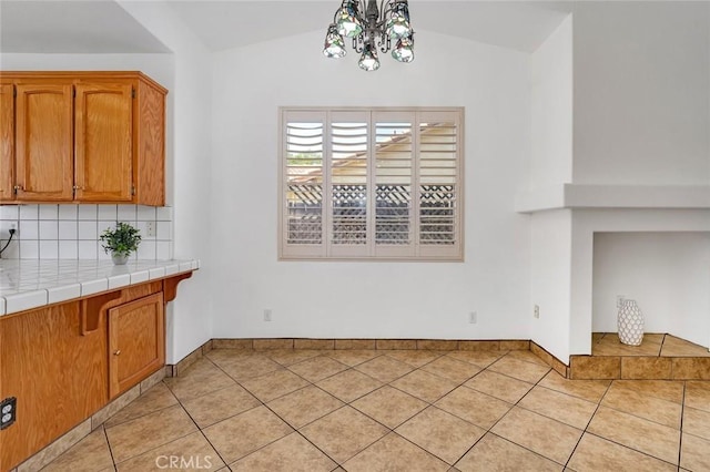 658 Tusky Ave, Los Banos, CA 93635 - unfurnished dining area featuring light tile patterned floors, vaulted ceiling, and a chandelier