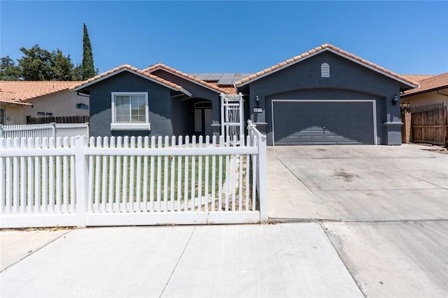 658 Tusky Ave, Los Banos, CA 93635 - view of front of house featuring a tiled roof, a fenced front yard, driveway, stucco siding, and an attached garage