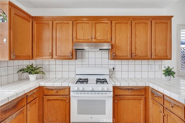 658 Tusky Ave, Los Banos, CA 93635 - kitchen with white range with gas stovetop, under cabinet range hood, tasteful backsplash, and brown cabinetry