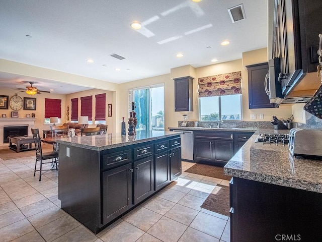 9275 Serenity St, Riverside, CA 92508 - kitchen with appliances with stainless steel finishes, dark cabinetry, a center island, open floor plan, and a ceiling fan