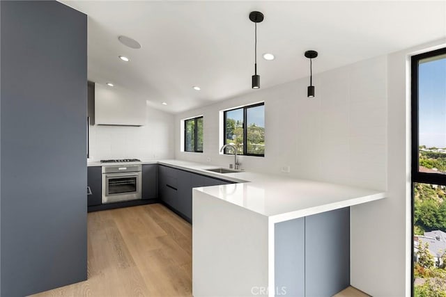 9336 Lloydcrest Dr, Beverly Hills, CA 90210 - kitchen featuring appliances with stainless steel finishes, light wood-style flooring, a peninsula, gray cabinetry, and hanging light fixtures