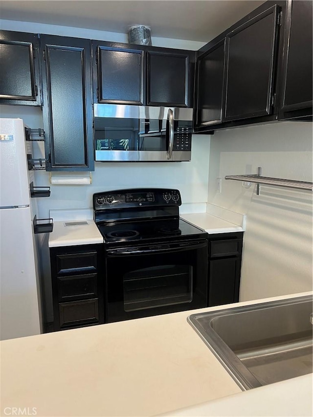 5257 Radford Ave Unit 308, Valley Village, CA 91607 - kitchen with stainless steel microwave, electric range, dark cabinetry, and light countertops