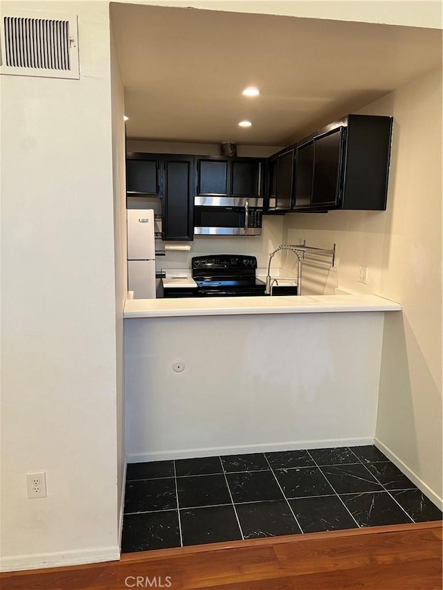 5257 Radford Ave Unit 308, Valley Village, CA 91607 - kitchen featuring stainless steel microwave, black / electric stove, freestanding refrigerator, dark cabinetry, and recessed lighting