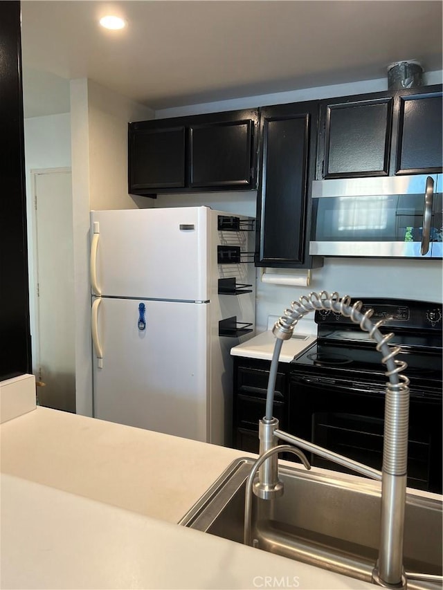 5257 Radford Ave Unit 308, Valley Village, CA 91607 - kitchen with freestanding refrigerator, stainless steel microwave, dark cabinets, black electric range oven, and light countertops
