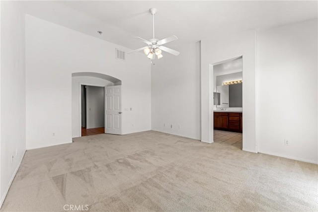 42619 Meridian Way, Lancaster, CA 93536 - unfurnished living room featuring light colored carpet, arched walkways, a ceiling fan, and a towering ceiling