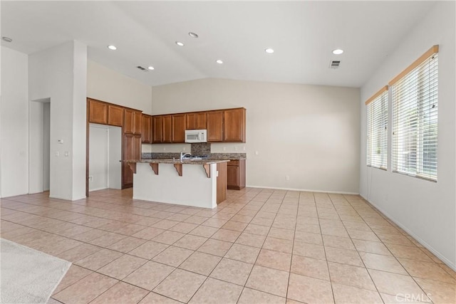 42619 Meridian Way, Lancaster, CA 93536 - kitchen featuring white microwave, light tile patterned flooring, a kitchen bar, brown cabinetry, and recessed lighting