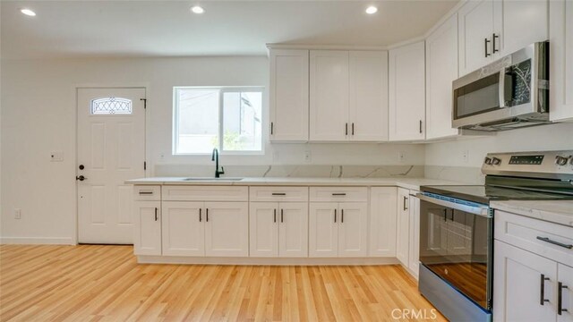 856 W 47th St, Los Angeles, CA 90037 - kitchen with appliances with stainless steel finishes, light wood-type flooring, recessed lighting, white cabinetry, and light stone countertops