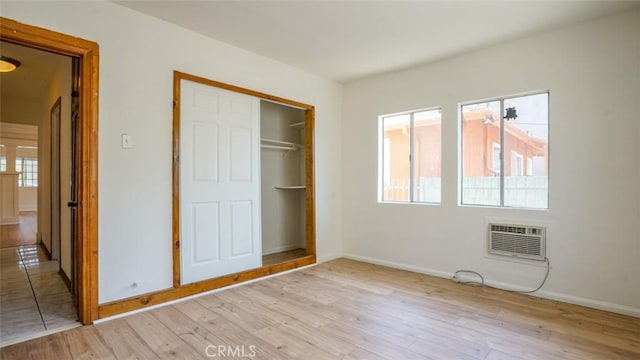 856 W 47th St, Los Angeles, CA 90037 - unfurnished bedroom with an AC wall unit, light wood finished floors, and a closet