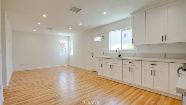 856 W 47th St, Los Angeles, CA 90037 - kitchen with light wood-style floors, recessed lighting, white cabinetry, open floor plan, and light stone countertops
