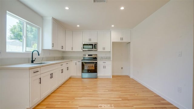 856 W 47th St, Los Angeles, CA 90037 - kitchen featuring appliances with stainless steel finishes, light wood-style floors, recessed lighting, white cabinets, and light countertops