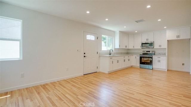 856 W 47th St, Los Angeles, CA 90037 - kitchen featuring appliances with stainless steel finishes, light wood finished floors, light countertops, white cabinetry, and recessed lighting