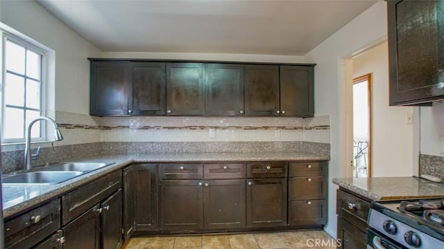 856 W 47th St, Los Angeles, CA 90037 - kitchen featuring dark brown cabinets, decorative backsplash, light tile patterned flooring, and stone countertops