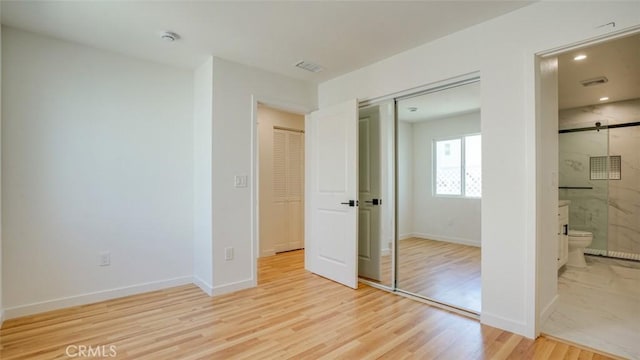 856 W 47th St, Los Angeles, CA 90037 - unfurnished bedroom with light wood-style flooring, a closet, a barn door, connected bathroom, and recessed lighting
