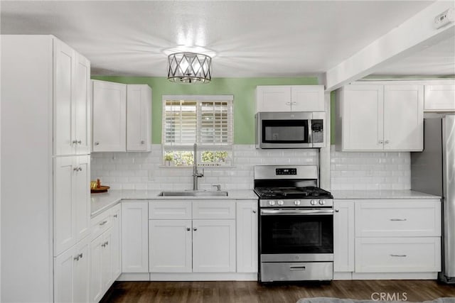 1003 Stevenson St, Colton, CA 92324 - kitchen with stainless steel appliances, white cabinetry, decorative backsplash, and dark wood finished floors