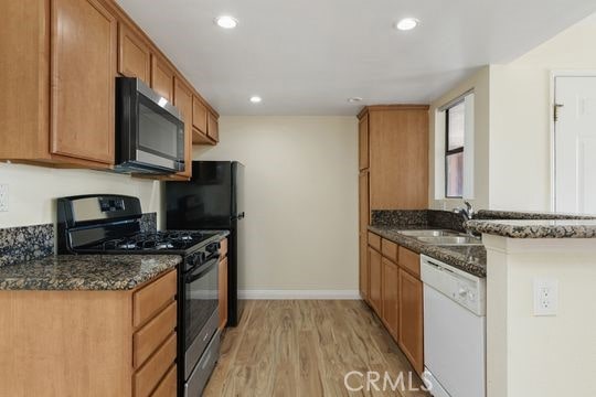 1313 Massachusettes Ave Unit 203, Riverside, CA 92507 - kitchen with stainless steel microwave, white dishwasher, black gas stove, light wood finished floors, and dark stone counters