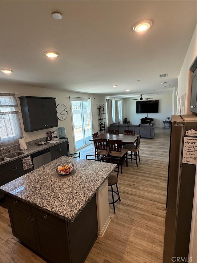12708 Ojo Caliente St, Victorville, CA 92392 - kitchen with open floor plan, stone countertops, a kitchen island, light wood-style flooring, and recessed lighting