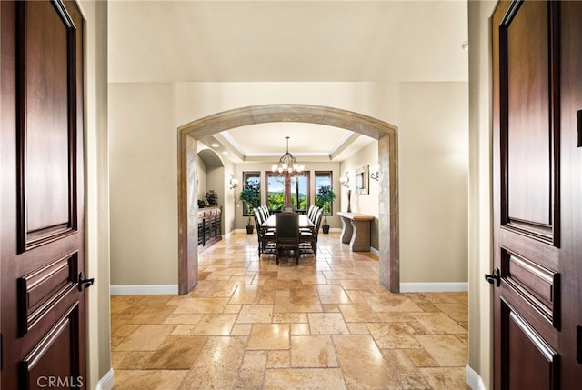 43650 La Cruz Dr, Temecula, CA 92590 - foyer with arched walkways, a chandelier, stone tile flooring, a raised ceiling, and crown molding