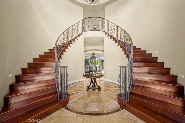 43650 La Cruz Dr, Temecula, CA 92590 - stairs featuring inlaid floor details, a high ceiling, a chandelier, and arched walkways