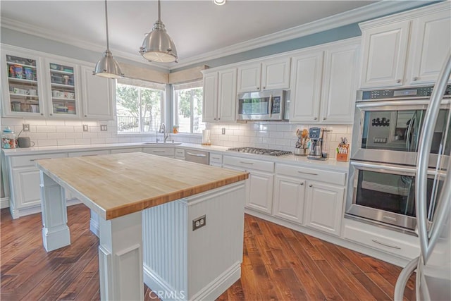 25531 Durant Pl, Stevenson Ranch, CA 91381 - kitchen with appliances with stainless steel finishes, white cabinetry, dark wood-style floors, crown molding, and tasteful backsplash