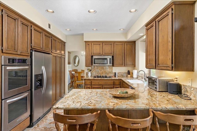 4635 Allende Ave, Oceanside, CA 92057 - kitchen with stainless steel appliances, a peninsula, a kitchen breakfast bar, light stone countertops, and recessed lighting