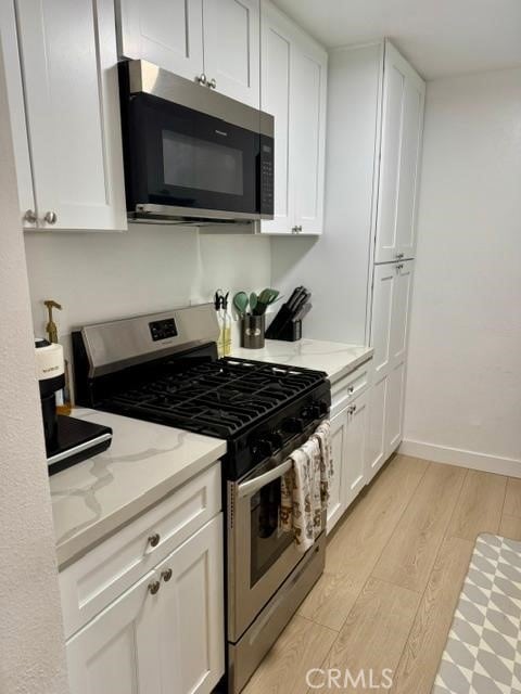 5700 Etiwanda Ave Unit 105, Tarzana, CA 91356 - kitchen featuring appliances with stainless steel finishes, white cabinetry, light stone countertops, and light wood finished floors
