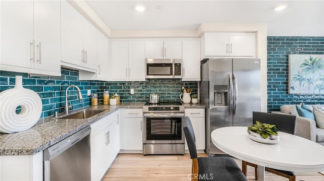 7415 Fig Grove St, Riverside, CA 92507 - kitchen featuring stainless steel appliances, light stone countertops, white cabinetry, light wood-style flooring, and tasteful backsplash
