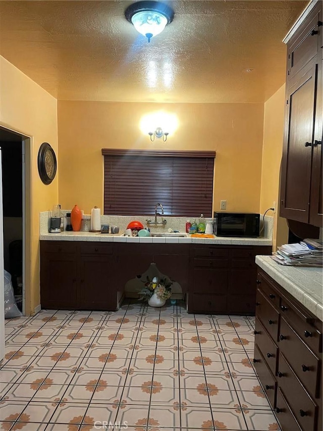 10430 San Jose Ave, South Gate, CA 90280 - kitchen with light floors, dark brown cabinets, tile counters, and a textured ceiling
