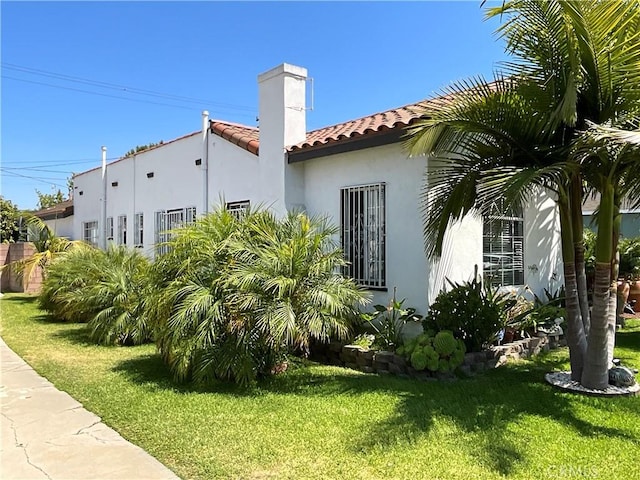 10430 San Jose Ave, South Gate, CA 90280 - view of side of property with a tiled roof, stucco siding, a chimney, and a yard