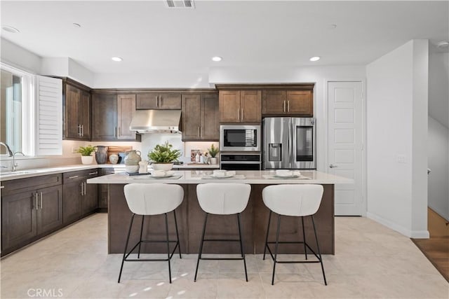 536 Cultivate, Irvine, CA 92618 - kitchen with stainless steel appliances, under cabinet range hood, a kitchen island, dark brown cabinets, and recessed lighting