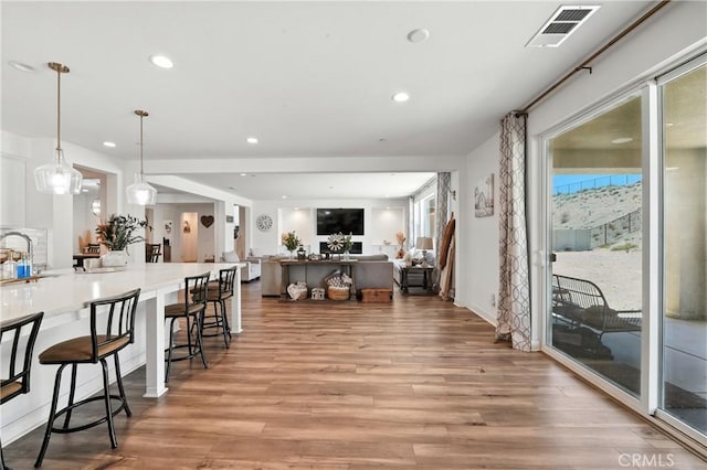 3969 Eliopulos Ranch Dr, Palmdale, CA 93551 - kitchen with light wood-type flooring, a breakfast bar area, recessed lighting, white cabinets, and decorative light fixtures