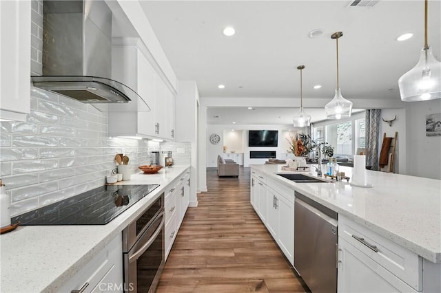 3969 Eliopulos Ranch Dr, Palmdale, CA 93551 - kitchen with stainless steel appliances, wall chimney range hood, open floor plan, wood finished floors, and white cabinets