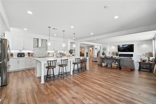 3969 Eliopulos Ranch Dr, Palmdale, CA 93551 - kitchen featuring freestanding refrigerator, wall chimney range hood, open floor plan, a kitchen bar, and light countertops
