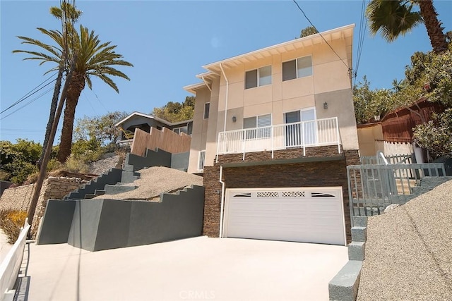 4215 Portola Ave, Los Angeles, CA 90032 - view of front of house with stone siding, an attached garage, a balcony, concrete driveway, and stucco siding