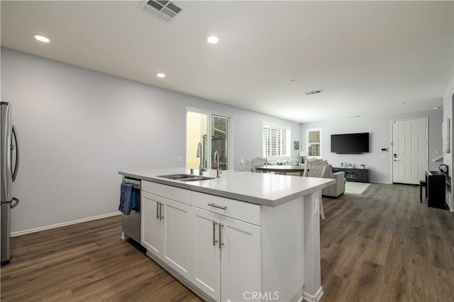 157 Ambrosia Ct, Perris, CA 92571 - kitchen featuring appliances with stainless steel finishes, white cabinetry, dark wood-style flooring, a kitchen island with sink, and light countertops
