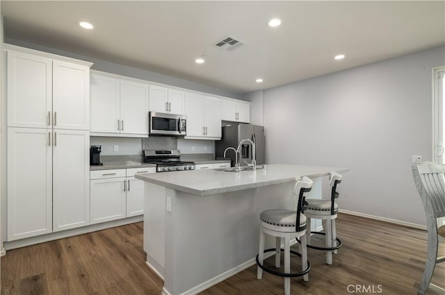 157 Ambrosia Ct, Perris, CA 92571 - kitchen featuring stainless steel appliances, a kitchen island with sink, dark wood-style flooring, white cabinets, and recessed lighting