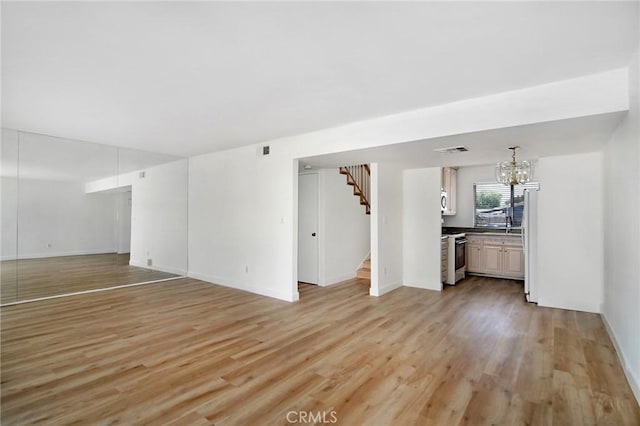 18931 Kittridge St Unit 73, Reseda, CA 91335 - unfurnished living room with stairway, light wood-style flooring, and a chandelier